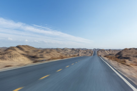 road speed motion blur, undulating desert wilderness highway against a blue skyの写真素材