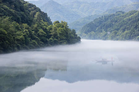 cast fishing net on the foggy river, beautiful Dongjiang Lake landscape in morning, Chenzhou City, Hunan Province, China.の写真素材