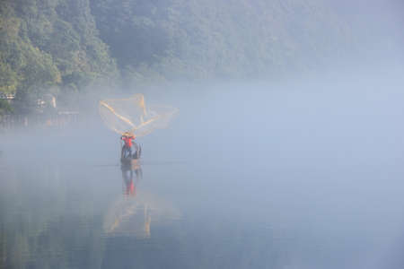 casting fishing net closeup on mist river, beautiful Dongjiang Lake landscape in morning, Hunan Province, China.の写真素材