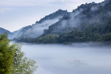 foggy little Dongjiang River landscape, traditional fishing boat in mist, Chenzhou City, Hunan Province, China.の写真素材