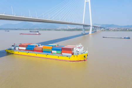 container ship sailing on inland river under cable-stayed bridge, the Yangtze river water transportation scene, Hubei province, Chinaの写真素材