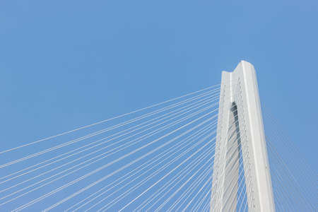 modern bridge background, cable-stayed bridge close-up, main tower and cable against a blue skyの写真素材