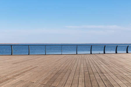 lake view and wooden floor with railing against a blue sky, natural outdoors backgroundの写真素材