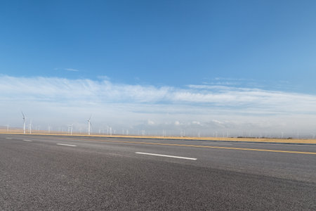 empty asphalt road with wind farm against a blue skyの写真素材