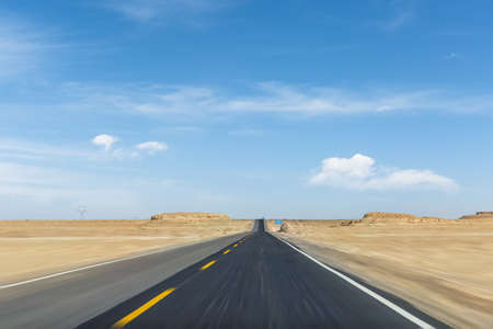 highway speed motion blur, asphalt road through the wind erosion physiognomy against a blue sky, Qinghai province, China.の写真素材