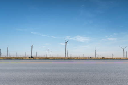 wind turbines by the road, empty asphalt highway with wind farm, new energy background.の写真素材