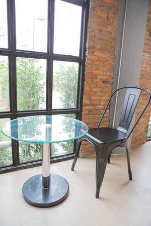 Table and chair by the window is located in the building.
