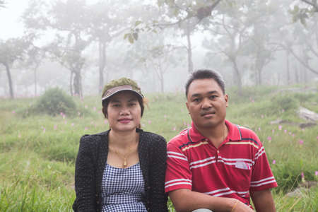 Man and woman sit on the mountain in the morning fog.の写真素材