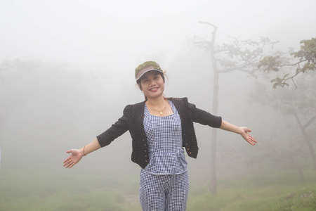 A woman standing on a mountain in the morning with fog.の写真素材