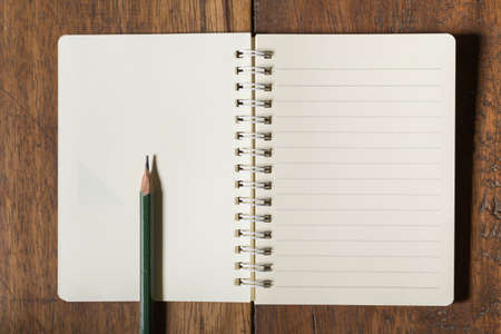 Notebook and pencil on old wooden floor.