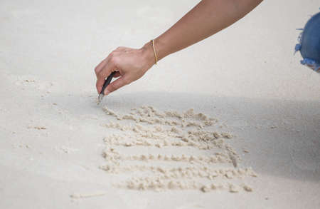 The hand is writing on the beach.の写真素材