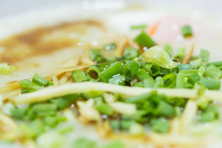 Finely sliced spring onions sprinkled on pork congee.の写真素材
