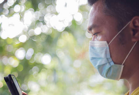 A man wearing a surgical face mask works over the phone at home.