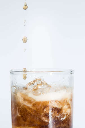 Black water falls on a glass on a white background.