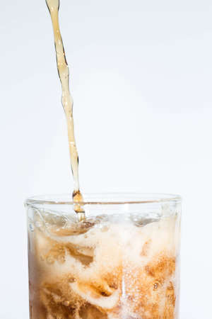 Black water falls on a glass on a white background.の写真素材