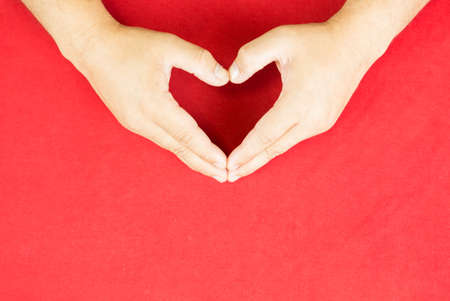 Heart shaped hands on the red background.の写真素材