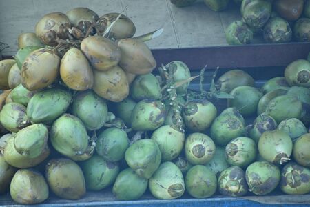 Fresh raw yellow and green coconuts fruits, selling green and yellow coconuts on the road side. The...