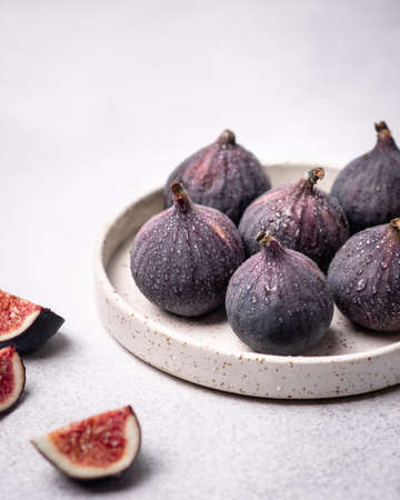 figs on a ceramic plate on a table on a light backgroundの写真素材
