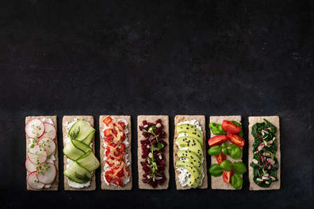 Different kinds of vegetarian sandwiches on a black background. Top view, place for text.の写真素材