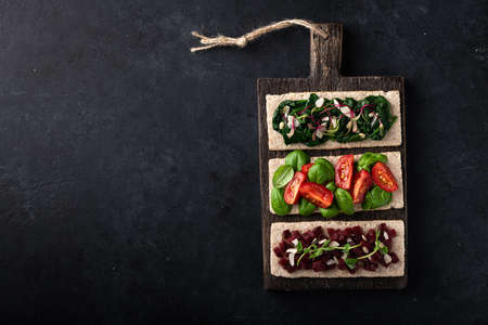 vegan sandwiches with spinach, nuts, tomatoes, basil, beets and micro greens on a black background. View from above.の写真素材