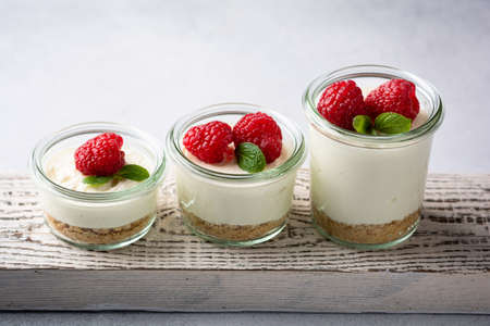cheesecake in a glass decorated with raspberries and mint on a gray backgroundの写真素材