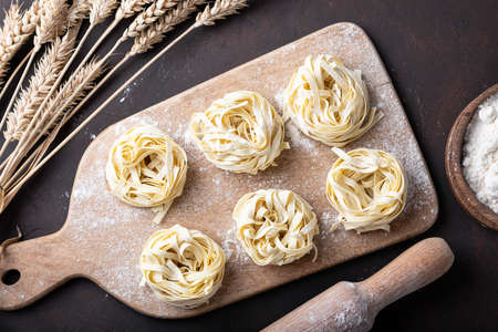 Raw uncooked homemade italian pasta tagliatelle on a darkの写真素材
