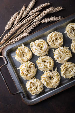 Raw uncooked homemade italian pasta tagliatelle on a darkの写真素材