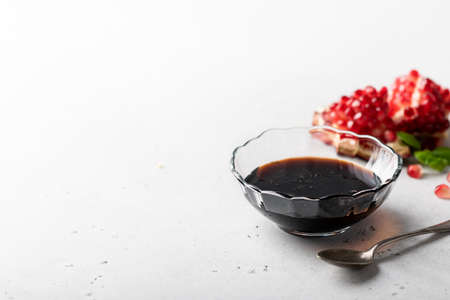 pomegranate sauce in a glass jar on a light background, place for textの写真素材