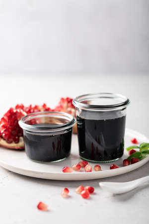 pomegranate sauce in a glass jar on a light background, place for textの写真素材