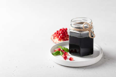pomegranate sauce in a glass jar on a light background, place for textの写真素材