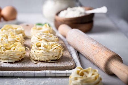 Raw uncooked homemade italian pasta tagliatelle on a light backgroundの写真素材