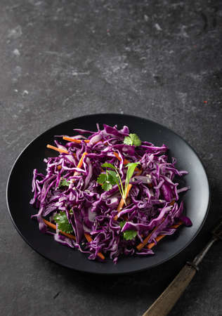 Red cabbage coleslaw with carrot on a dark background. Healthy food concept. の写真素材