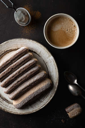 Italian savoiardi cookies with coffee on a dark background, dessert. View from above