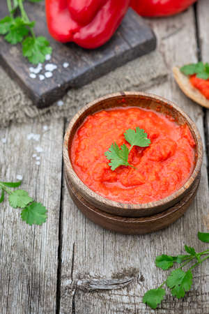 Balkan traditional dish ajvar in bowl on rustic wooden background, place for textの写真素材