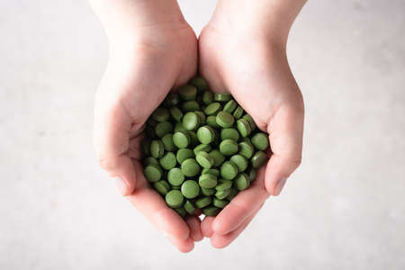 Chlorella pills in hand . Concept of superfood and detox.の写真素材