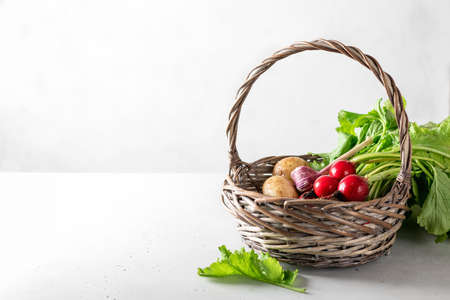 fresh garden vegetables in a basket on a light background, place for textの写真素材