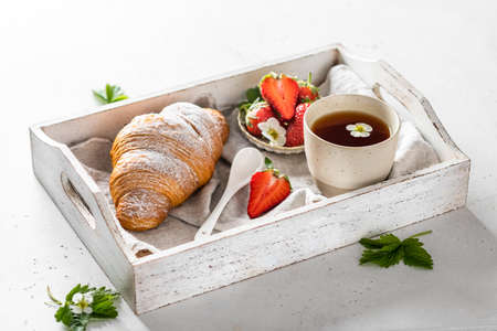 Croissant, tea and strawberries. Breakfast and morning concept