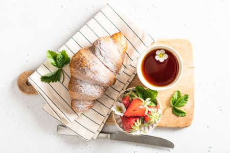 Croissant, tea and strawberries. Breakfast, morning and spring concept, view from aboveの写真素材