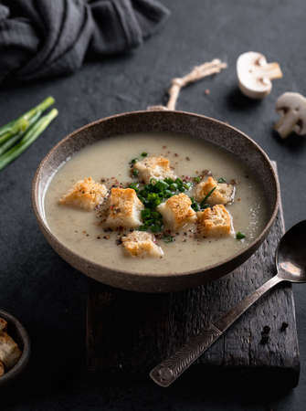 mushroom cream soup with champignons and croutons in a ceramic bowl on a dark backgroundの写真素材
