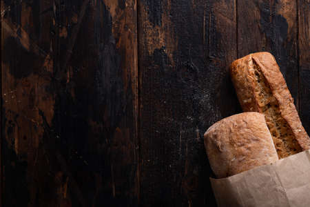 Fresh bread in a paper bag on an old wooden