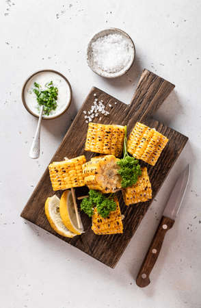 corn cobs grilled on a kitchen board on on a white backgroundの写真素材