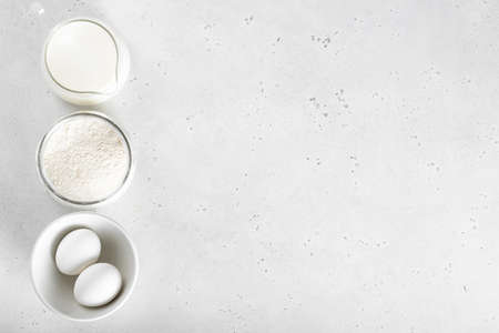 flour, egg, milk on a white table, view from above