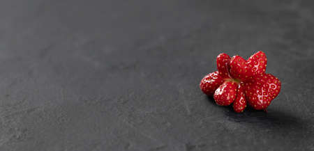ugly strawberry on a dark background, place for text