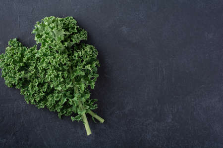 kale leaves on a dark background, top view, place for text