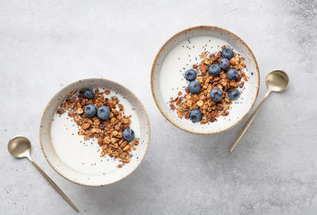 Breakfast, granola with yogurt, blueberries, chia seeds, pumpkin seeds on a light background, view...