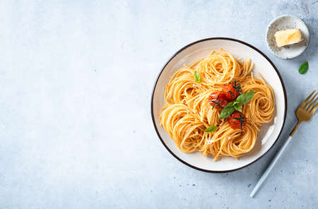 pasta with cherry tomatoes in a white plate on a light blue background, italian food.