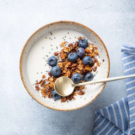 Breakfast, granola with yogurt, blueberries and chia seeds on a light blue background, top viewの写真素材