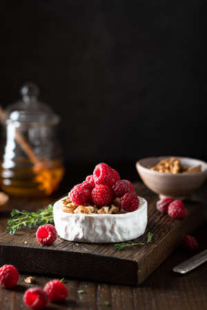brie or camembert cheese with raspberries and walnuts, dark background, selective focus,の写真素材