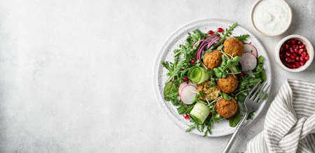 Falafel and vegetables salad on a white ceramic plate on concrete background, copy space. Vegetarian food conceptの写真素材