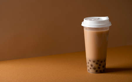 Taiwan milk bubble tea with tapioca in a plastic cup on a colored background, selective focus, copy...